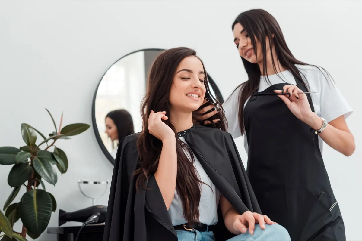 Stylist styling a smiling client's hair at Bella Glow Salon