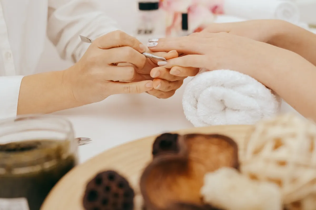 Manicurist shaping a client's nails at the spa table